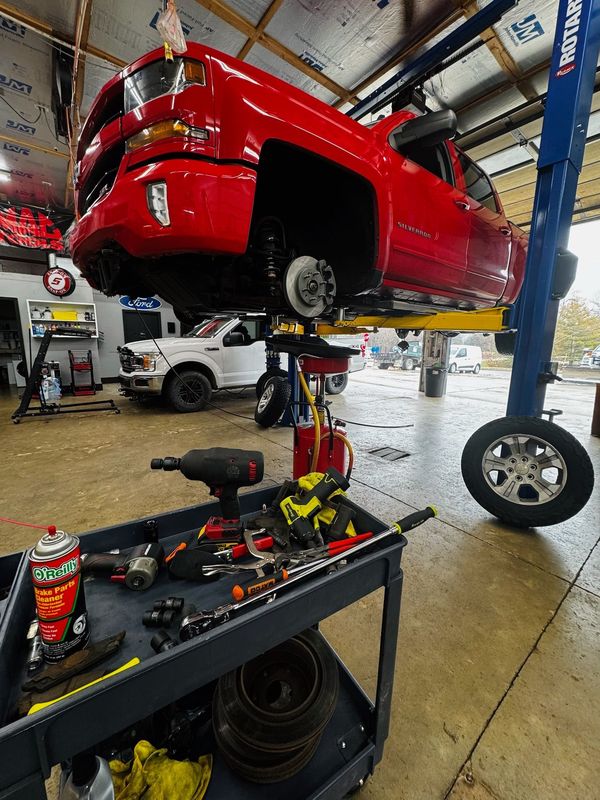 Red Dodge Ram pickup on a lift at Elite Diesel & Auto Works, a short drive from Grain Valley