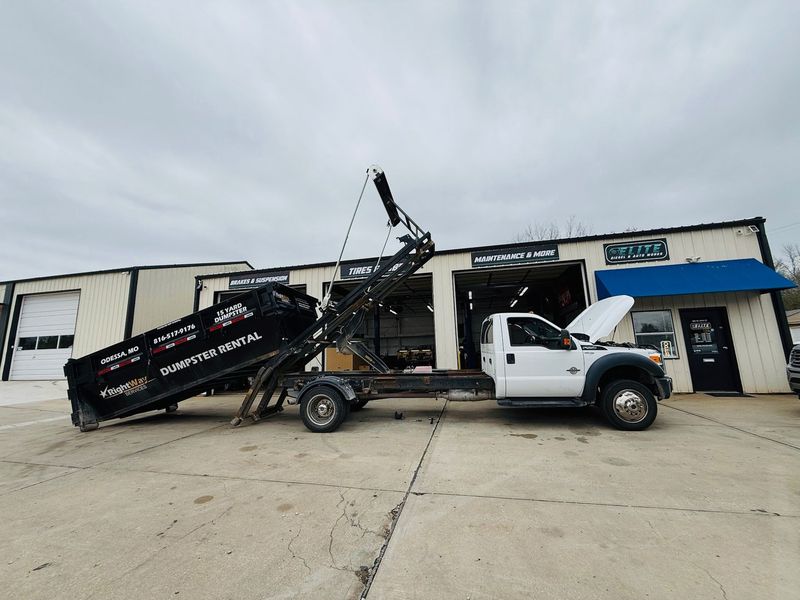 Ford Super Duty work truck with a roll-off dumpster trailer at Elite Diesel & Auto Works