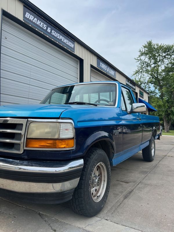 Blue classic Ford F-150 parked outside Elite Diesel & Auto Works near Bates City