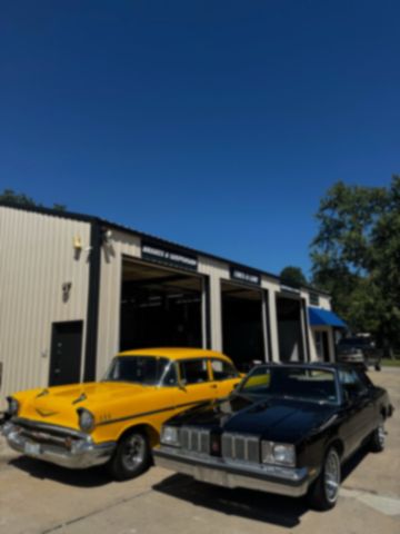 Two classic pickups parked in front of the shop at dusk