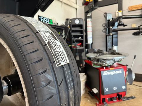 New Firestone Firehawk tire next to a Snap-on tire changer in the shop