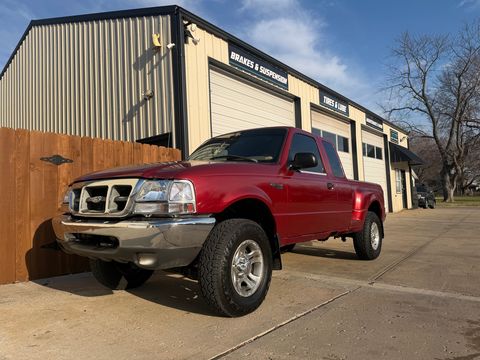 Red Ford Ranger pickup parked outside the shop's Brakes & Suspension and Tires & Lube bays