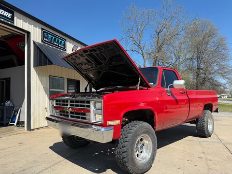 Red classic Chevrolet square-body pickup with the hood up outside the Elite shop