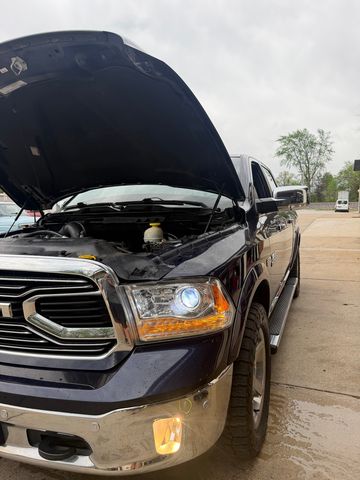 Dark blue Ram pickup with the hood open on the concrete in front of the shop