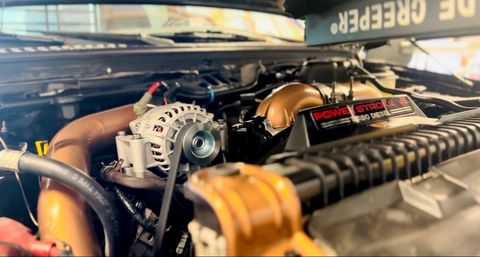 Ford Power Stroke V8 turbo diesel engine bay with copper-colored intake piping and a new alternator