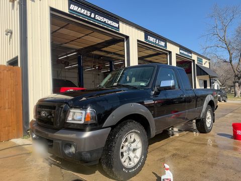 Black Ford Ranger extended-cab pickup, freshly washed, outside the shop's Brakes & Suspension bay