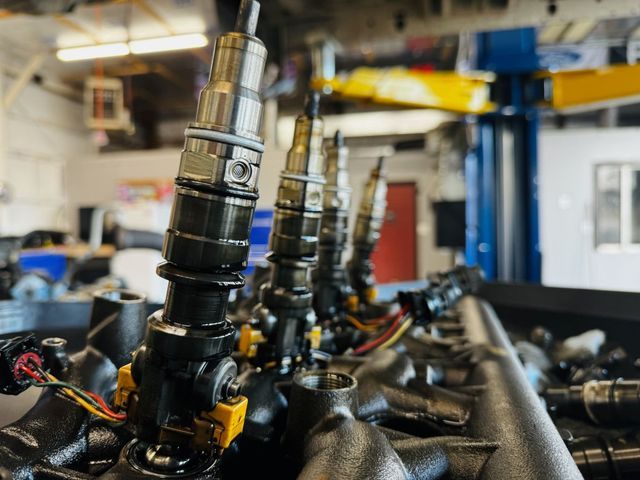 Diesel fuel injectors pulled from an engine on the workbench at Elite Diesel & Auto Works