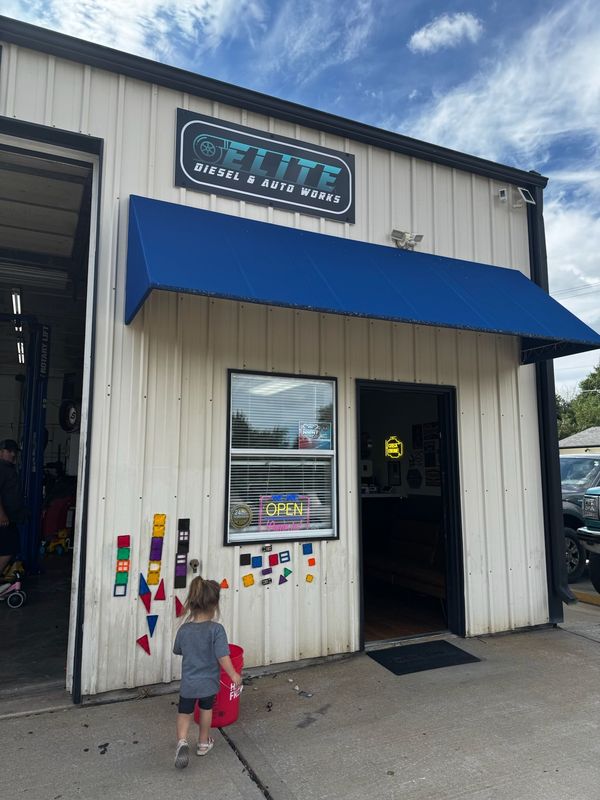 Front entrance of Elite Diesel & Auto Works with the blue awning and shop signs